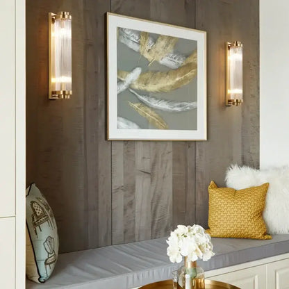 Modern gold decorbites crystal wall sconce featuring gold-framed abstract feathers in white silver and gold on gray background