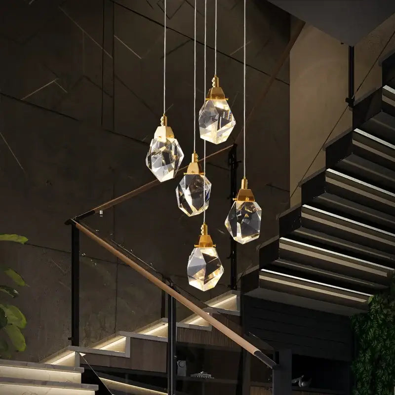 Five faceted crystal pendant lights with gold fixtures form a modern gold diamond crystal chandelier for living room lighting