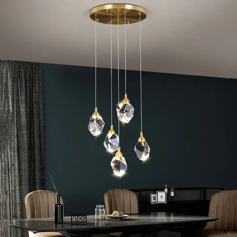 A modern gold diamond crystal led ceiling chandelier with five clear glass pendants for dining room lighting