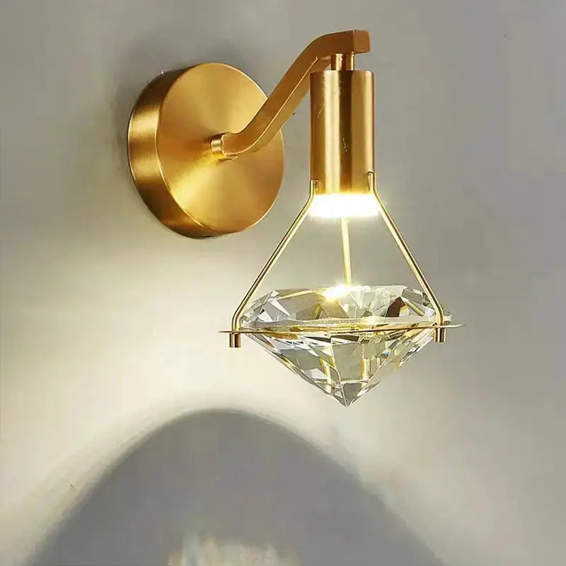 Modern gold wall lamp with a clear faceted diamond crystal pendant for stylish bedroom lighting