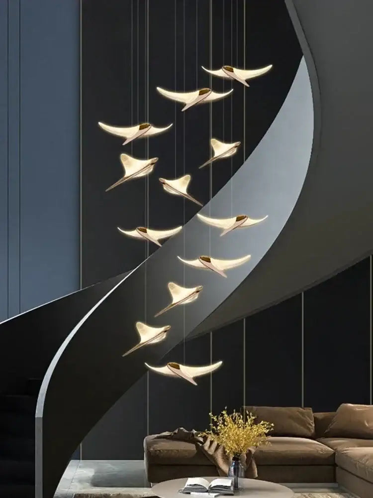 Modern gold-toned decorbites dolphin pendant chandelier lighting a sleek curved hotel lobby staircase setting