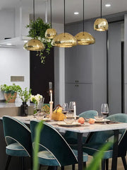 Modern gold dome pendant lamps with polished metallic surface and perforated detailing hang above dining table decorbites glass gold ceiling