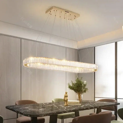 A modern gold decorbites crystal led chandelier with cascading crystal strands above a dark marble dining table