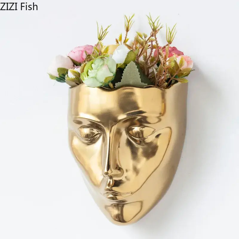 Modern gold decorbites ceramic wall-mounted vase shaped like a stylized human face filled with pink and white flowers