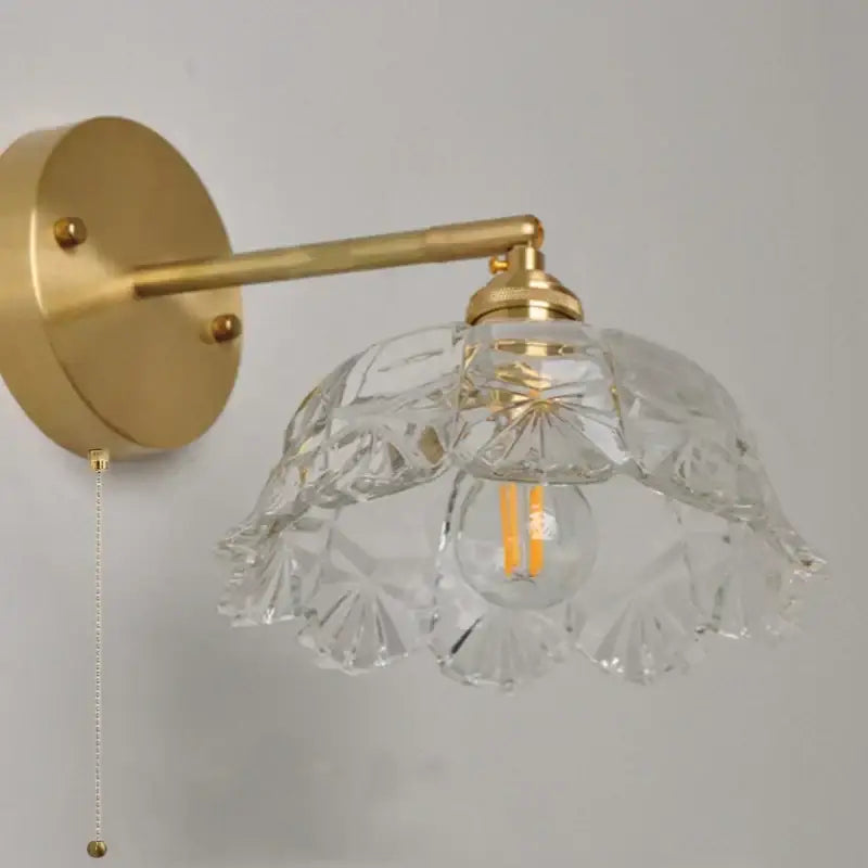 Modern gold faceted clear glass wall lamp with intricate cut patterns and a gold-toned metal arm for bedroom use