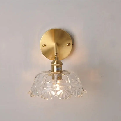 Modern gold faceted clear glass wall lamp with brass mounting plate and stem for bedroom wall light
