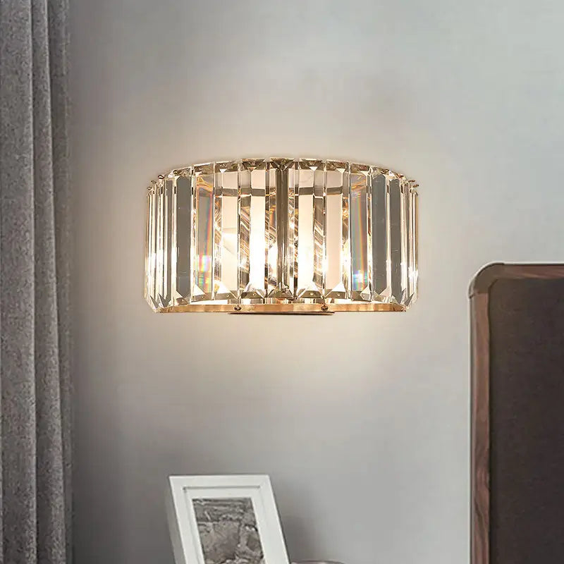 Modern wall sconce with a gold finish featuring a circular frame and faceted crystal rods for bedroom lighting