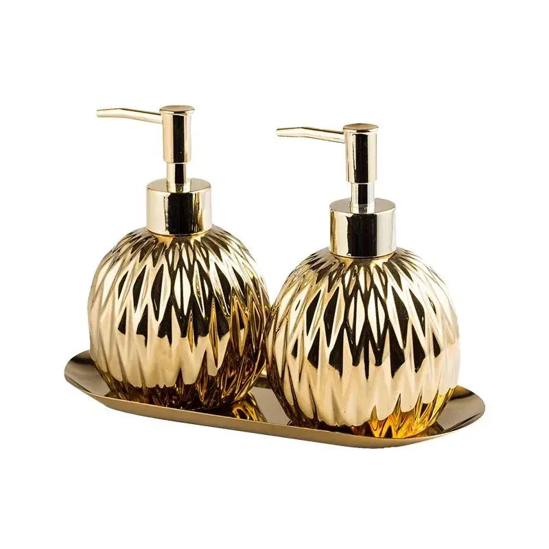 Modern gold faceted glass liquid soap dispenser and lotion set with matching pumps on coordinating gold tray for bathroom decor