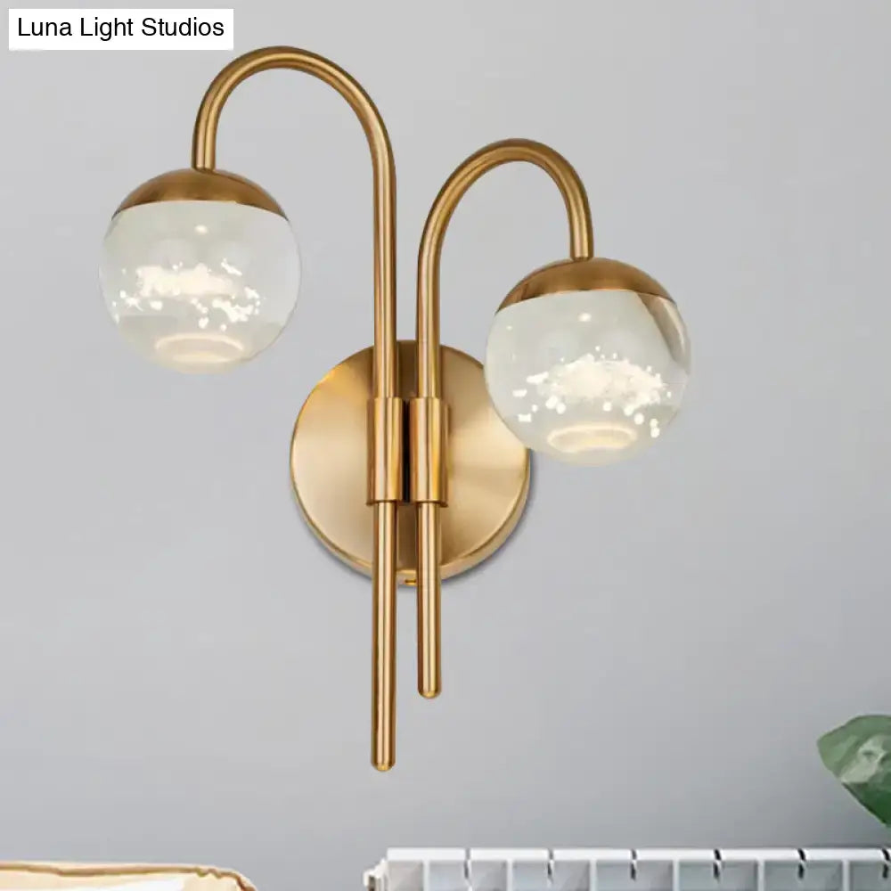 Modern gold finish wall sconce with brass curved arms and frosted glass globe shades for living room lighting