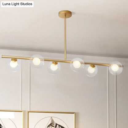 Modern gold finish linear pendant light with five clear glass globe shades for kitchen or dining areas