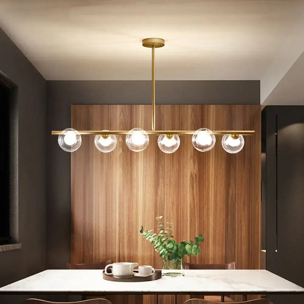 Modern gold finish linear pendant light with five clear glass globes for kitchen lighting