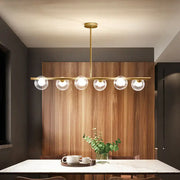 Modern gold finish linear pendant light with five clear glass globes for kitchen lighting