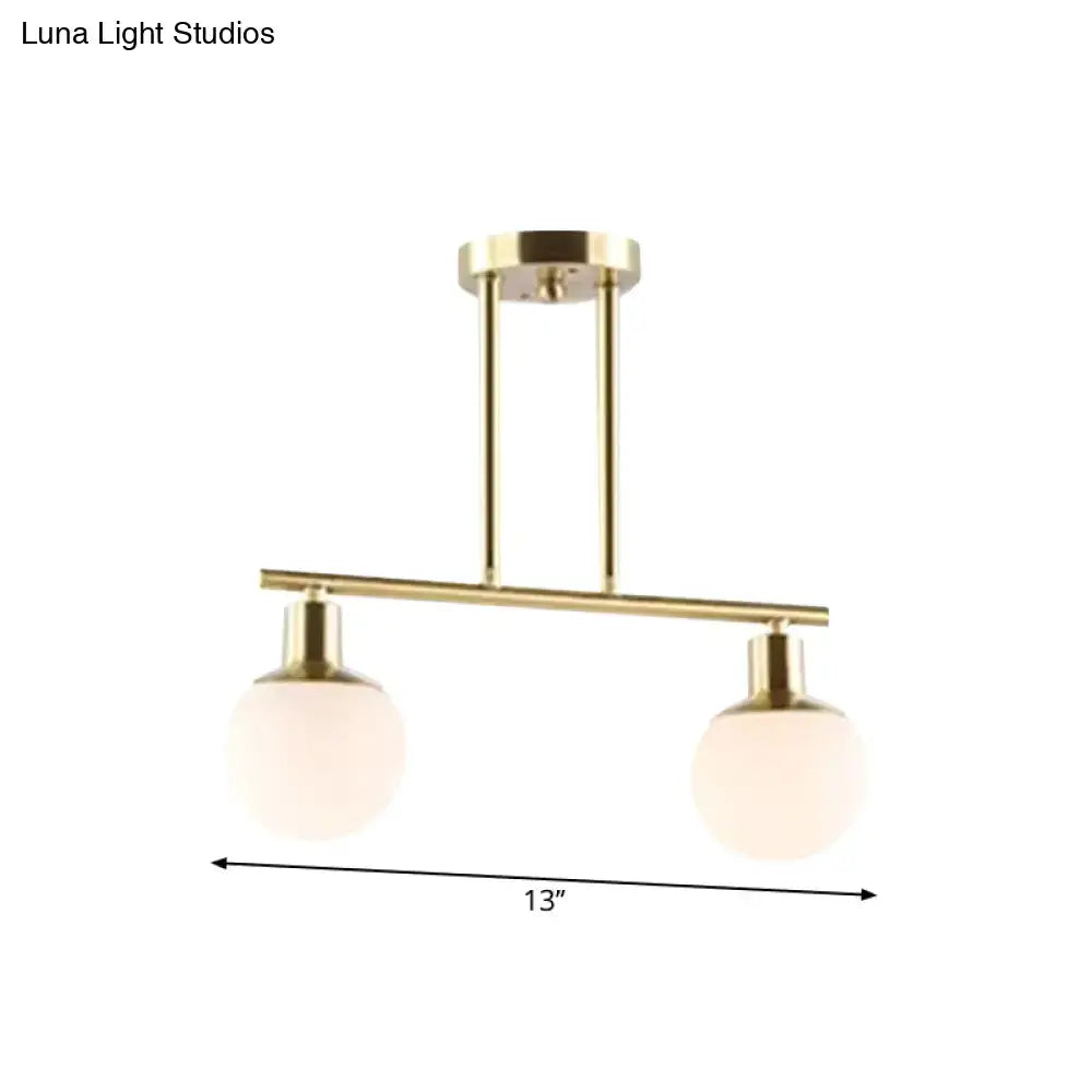 Modern brass linear chandelier pendant light with two frosted milk glass globe shades and gold finish