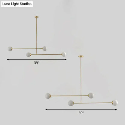 Modern minimalist pendant light with gold finish metal frame and five white opal glass globes with bulb base