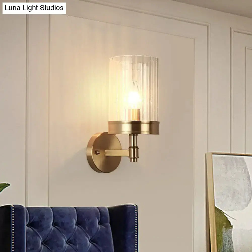 Brass-finished wall light with gold finish and clear glass cylinder shade suitable for bedroom color temperature control