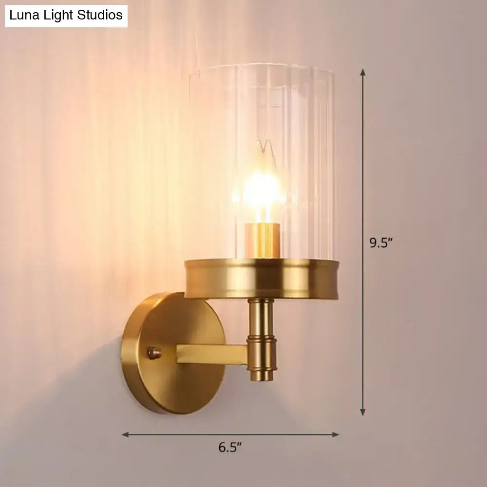 Modern gold finish wall light with a brass finish and clear glass shade showing exposed bulb and color temperature