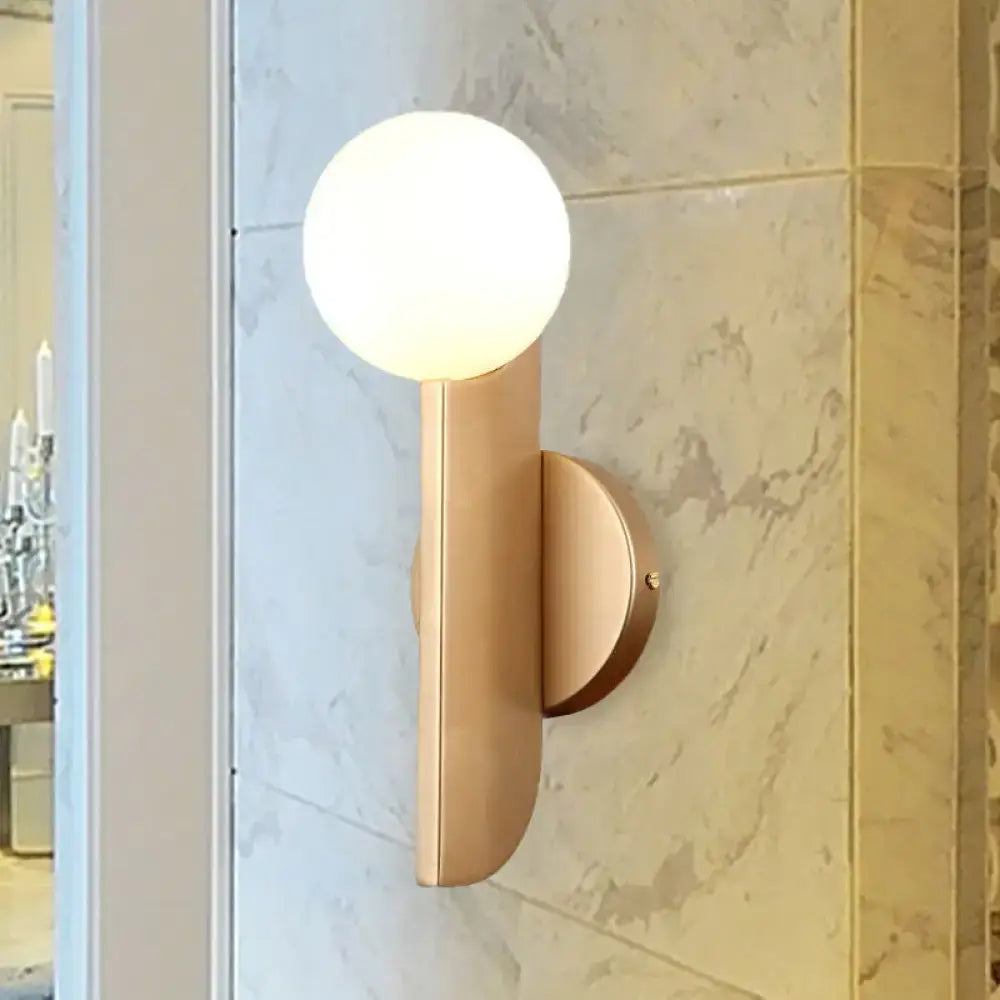 Modern gold finish wall sconce with sleek curved metal arm and milky glass shade for elegant bedroom lighting