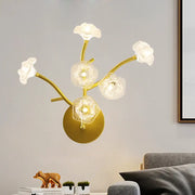 Gold-toned wall mount lamp with five translucent floral glass shades on curved branches for bedside light fixture