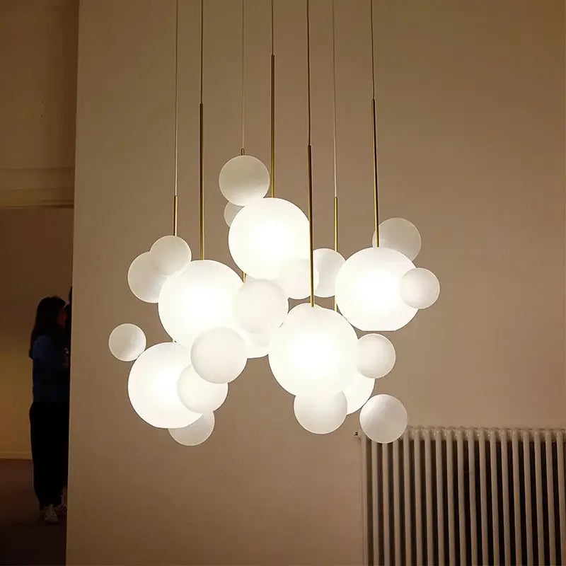 Modern gold pendant light featuring a frosted glass ball with white frosted glass and gold-toned rods for dining room