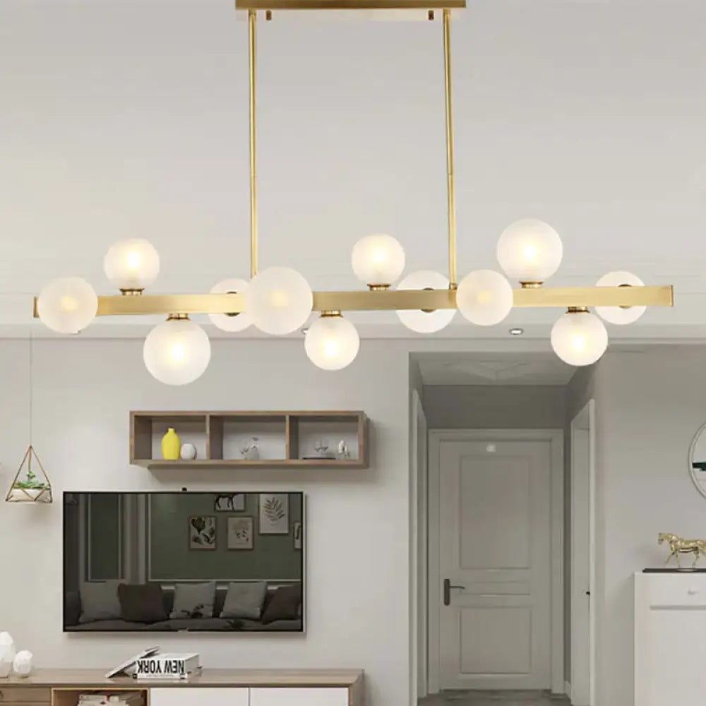 Modern gold pendant light with frosted glass globe bulbs on a sleek horizontal bar and adjustable chain cord length