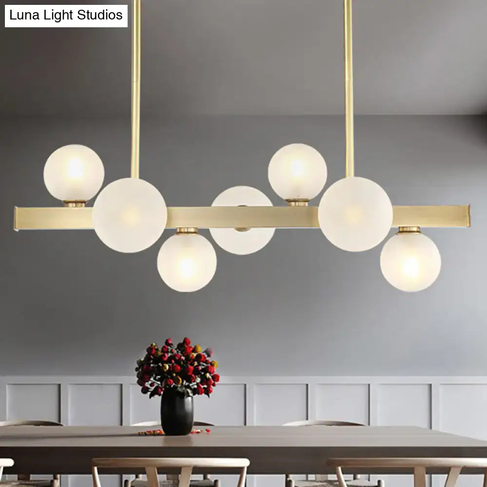 Modern gold pendant light with frosted glass globe bulbs and adjustable chain cord length for dining room island