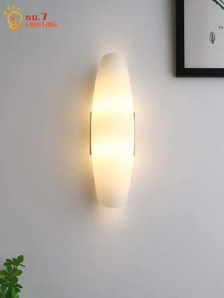 Modern gold frosted glass led wall lamp with oval shape and metallic accents emitting warm ambient light