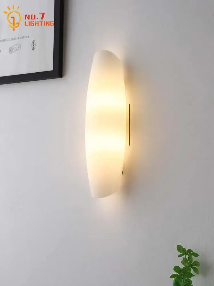Modern gold led wall lamp featuring a warm-toned oval frosted glass diffuser and minimalist metal mounting for bedroom use