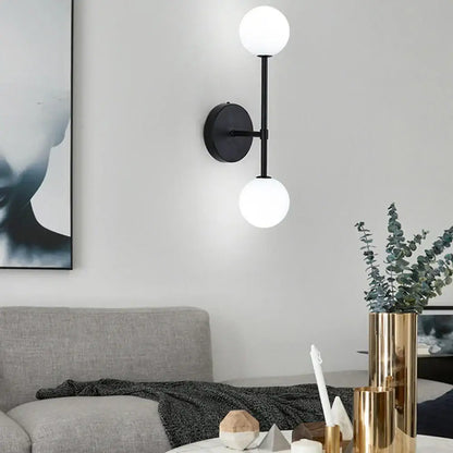 Black led wall sconce with two frosted glass globes for modern bedroom lighting