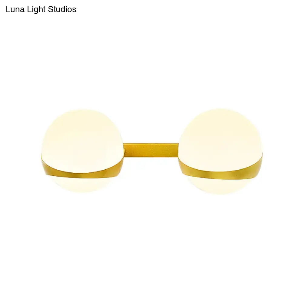 Modern gold wall sconce with two frosted glass globe shades direct wired for bedroom lighting
