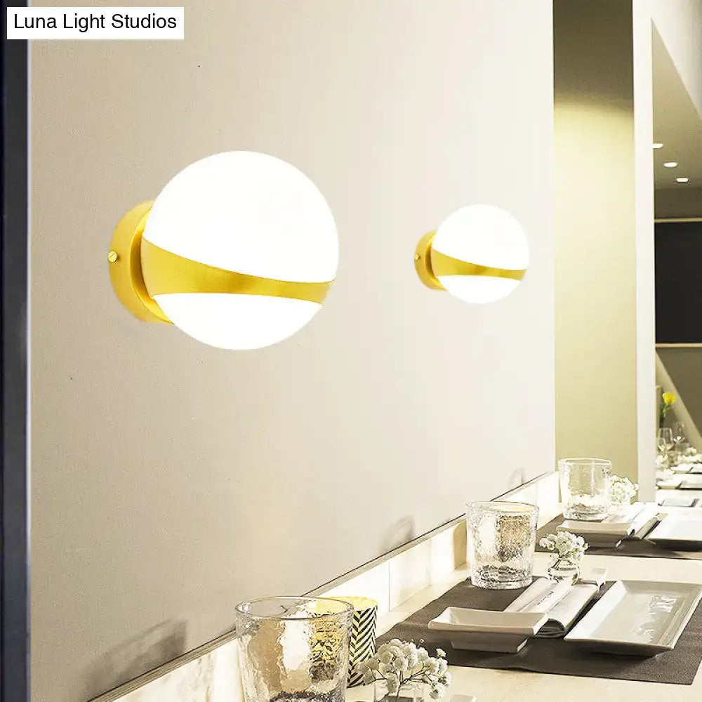 Modern gold frosted glass wall sconce with direct wired spherical design and gold accents for bedroom lighting