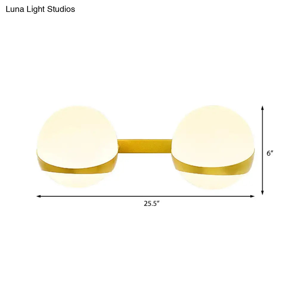 Modern gold wall sconce with two frosted glass globes direct wired for bedroom lighting use