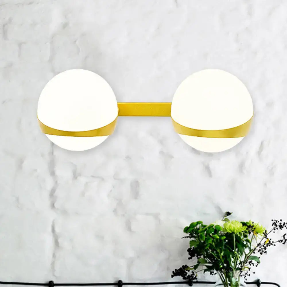 Modern gold frosted glass dual-head wall sconce with white spherical shades and direct wired installation for bedroom use