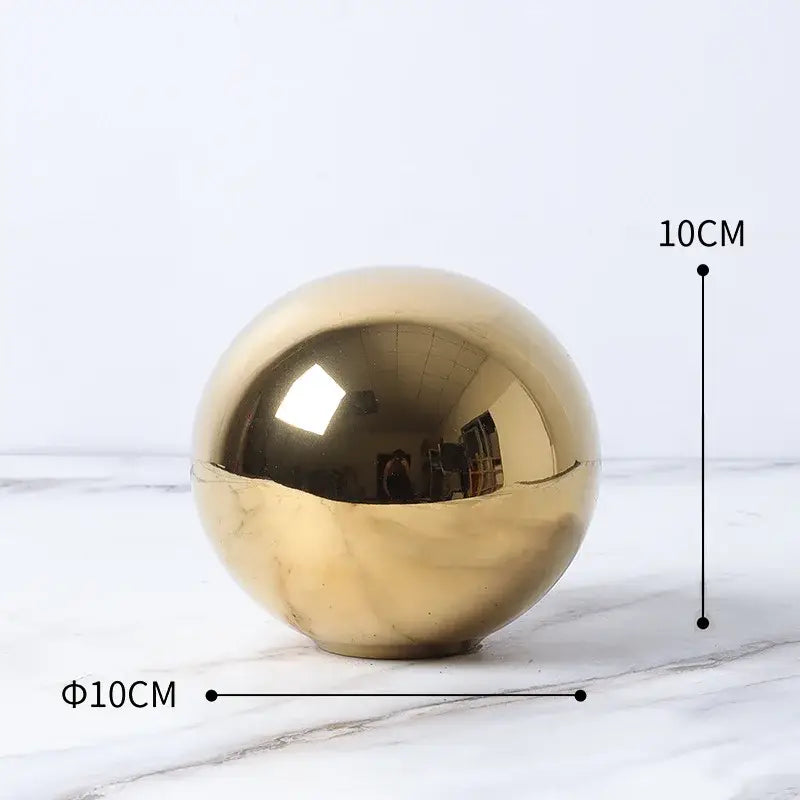 A polished gold-colored cube round statue with a reflective surface and 10cm diameter for modern living room decor