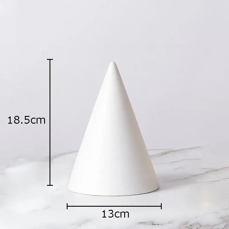 A sleek white ceramic cone with glossy finish and geometric lines paired with modern gold cube round statue decor