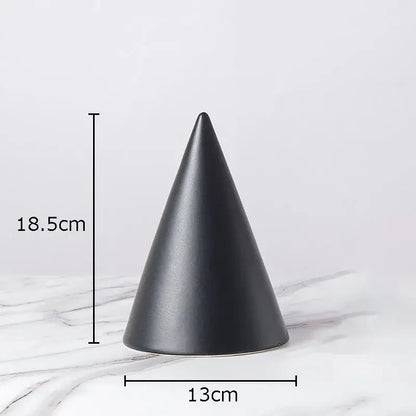 A sleek matte black ceramic cone contrasts with a modern gold geometric cube round statue for living room decor