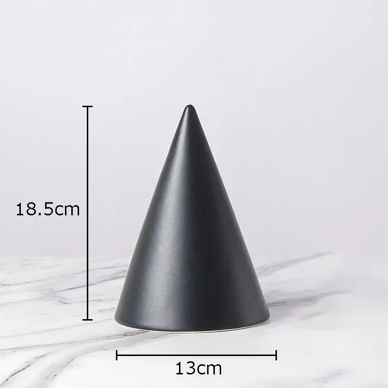 A sleek matte black ceramic cone contrasts with a modern gold geometric cube round statue for living room decor