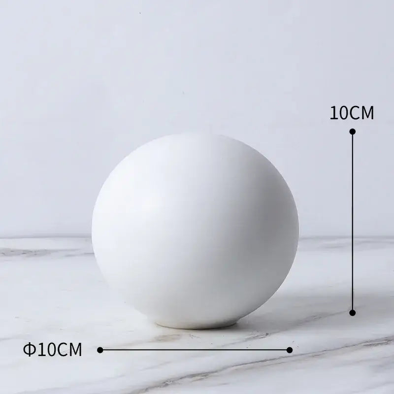 A smooth matte white ceramic sphere in a modern gold geometric cube round statue decor for living room