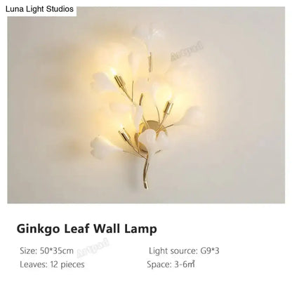 Modern gold ginkgo leaf porcelain wall sconce with delicate white leaf and gold-toned metal branches emitting warm glow
