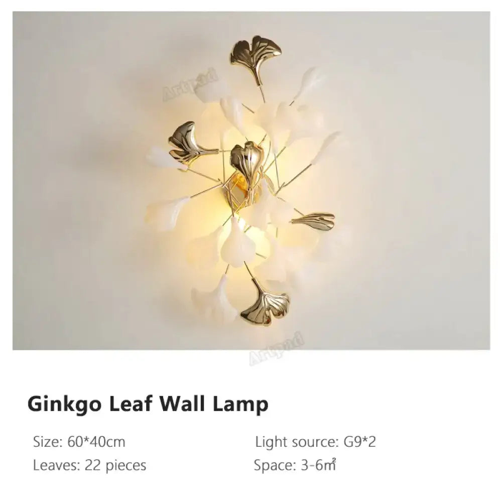 Modern gold ginkgo leaf porcelain wall sconce with metallic gold leaves and translucent white petals glowing warmly