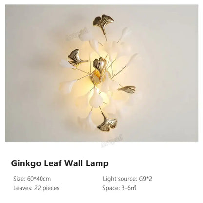 Modern gold ginkgo leaf porcelain wall sconce with metallic gold leaves and translucent white petals glowing warmly