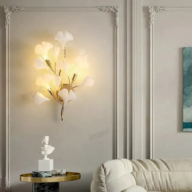 Modern gold ginkgo leaf porcelain wall sconce with elegant white glass leaves and gold-toned metal branches for bedroom lighting