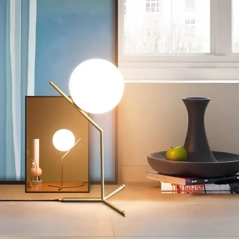 A modern brass-finished table lamp with a spherical frosted glass globe for decorbites glass ball led chandelier light