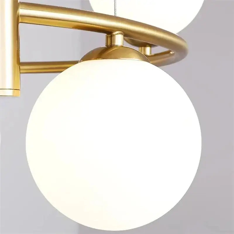 Modern gold glass ball pendant chandelier with gold-toned metal frame and frosted white glass globe for dining room decorbites glass ball