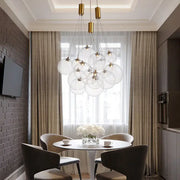 Modern gold pendant chandelier with clear glass ball shades hanging above a dining table as pendant light