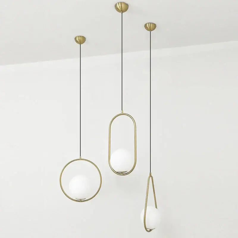 Three modern pendant lights with brass frames and frosted glass balls suspended by black cords for dining room decorbites glass ball pendant