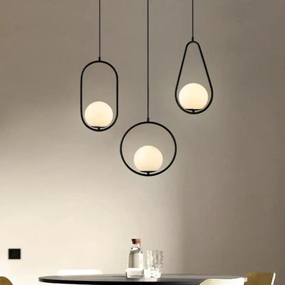 Three minimalist black metal frame pendant lights with warm frosted glass globes for modern dining room decorbites glass ball pendant
