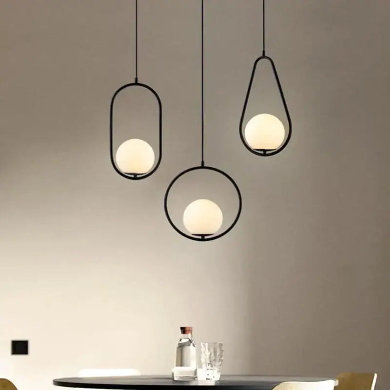 Three minimalist black metal frame pendant lights with warm frosted glass globes for modern dining room decorbites glass ball pendant