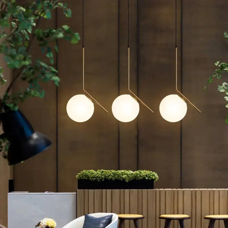 Three modern gold glass ball pendant lights with white glass shades and slender metal arms for dining room decorbites decor