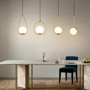 Modern gold glass ball pendant lights with frosted globes hang above a marble dining table decorbites glass ball pendant