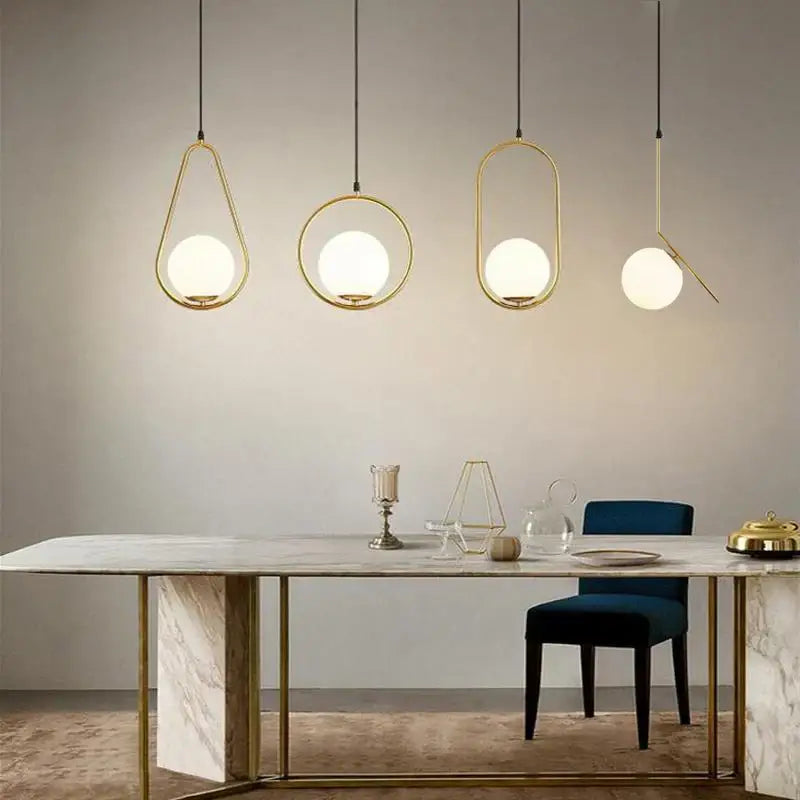 Modern gold glass ball pendant lights with frosted globes hang above a marble dining table decorbites glass ball pendant